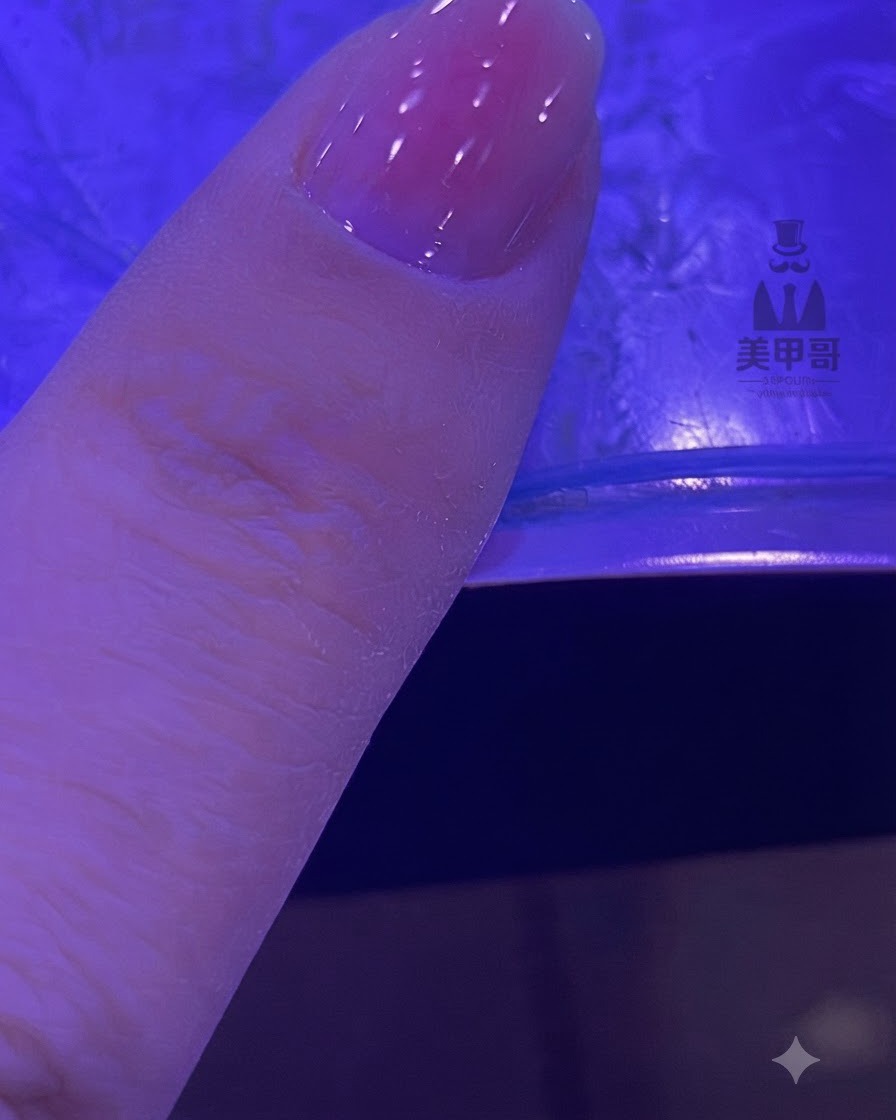 ブレンドされたピンクのグラデーションを持つ爪がUV/LEDランプの下で硬化している様子。