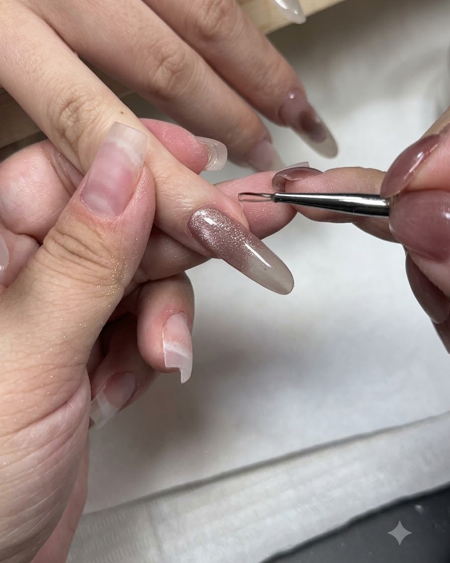 細いアート筆を使って、キャッツアイネイルの先端にノンワイプのアイシングジェルを乗せている様子。