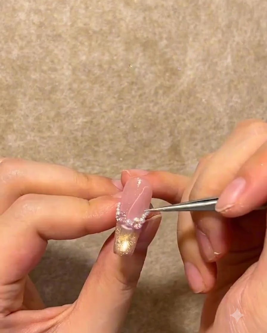 精密なピンセットを使って、フレンチのスマイルラインに沿って小さな白いパールとラインストーンを配置している様子。