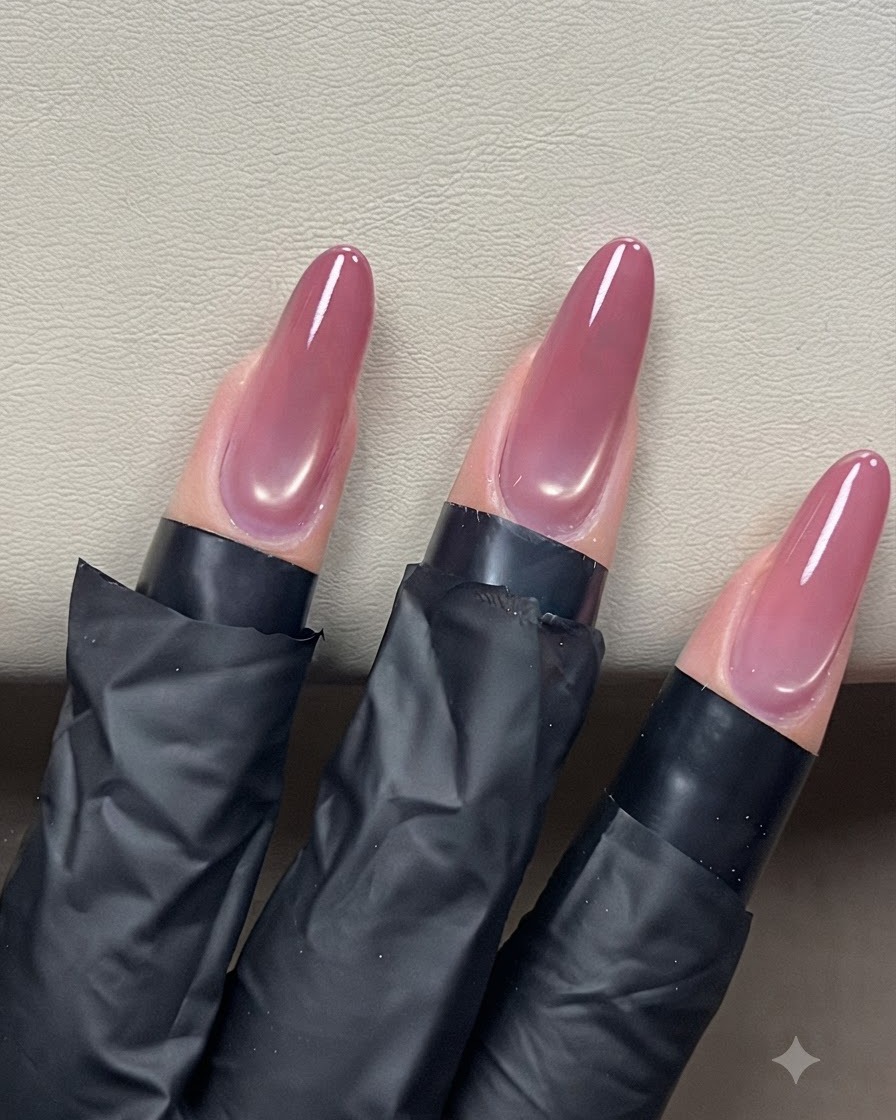 光沢のある仕上げのために、アーモンド型のキャッツアイネイルの上にクリアトップコートを滑らせているネイルブラシ。