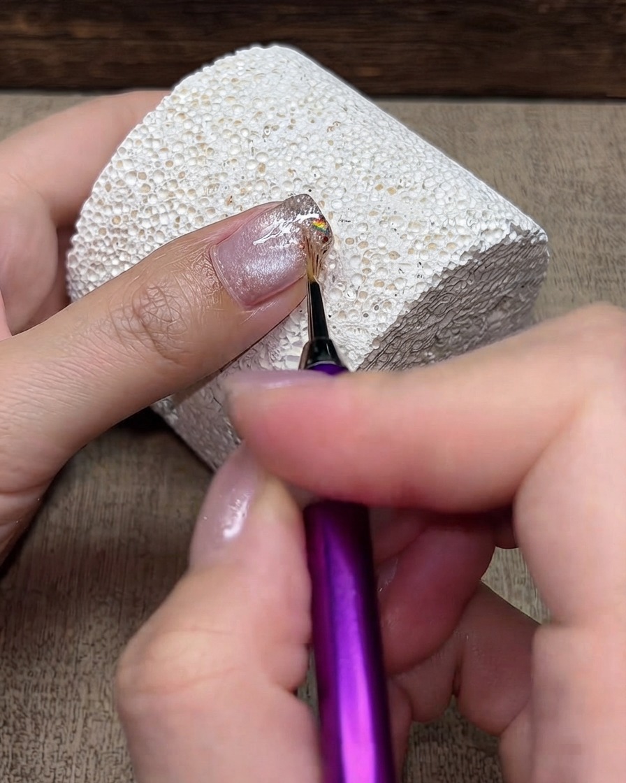 細かいアート筆を使って、きらめくグラデーションの表面を軽くなでるように作業している様子。