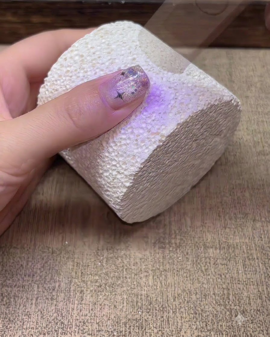 紫色のUV LEDネイルライトの下で手を当てて硬化させている様子。