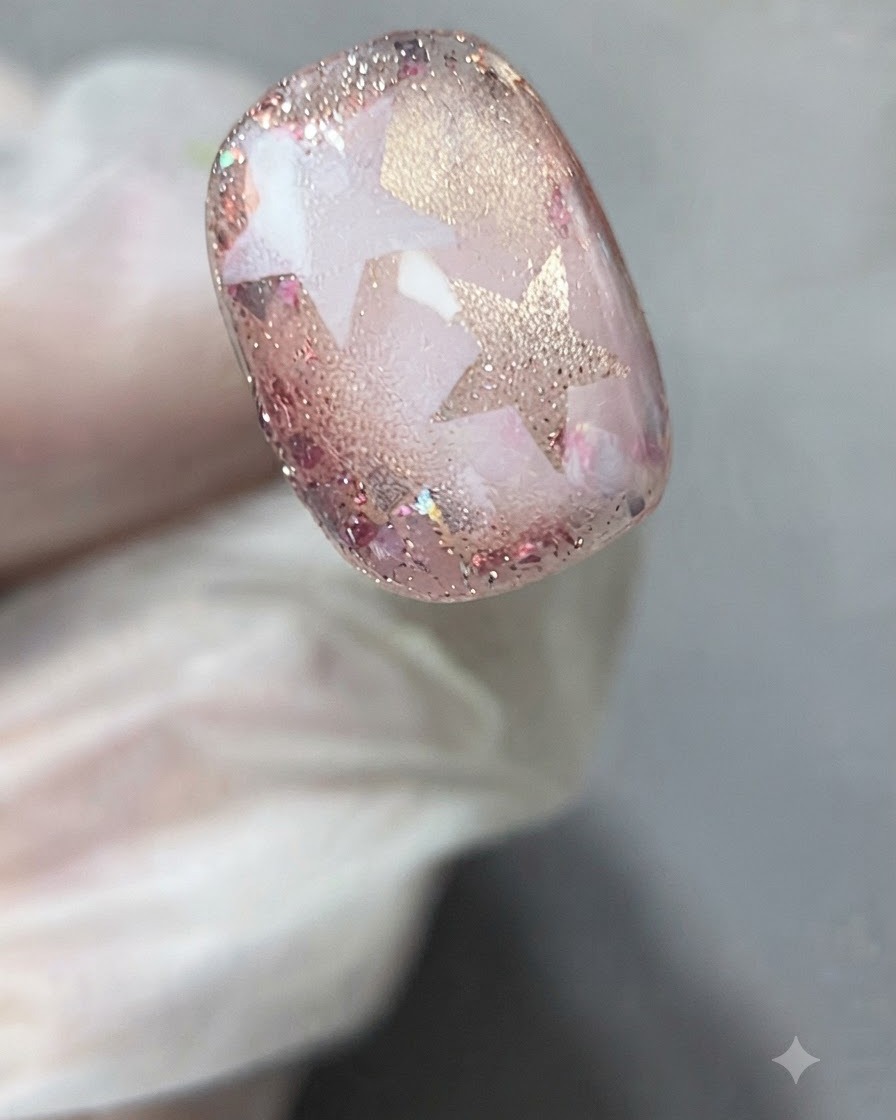 ピンセットや手袋をつけた指で、硬化させたネイルアートから星のステンシルを優しく剥がしている様子。