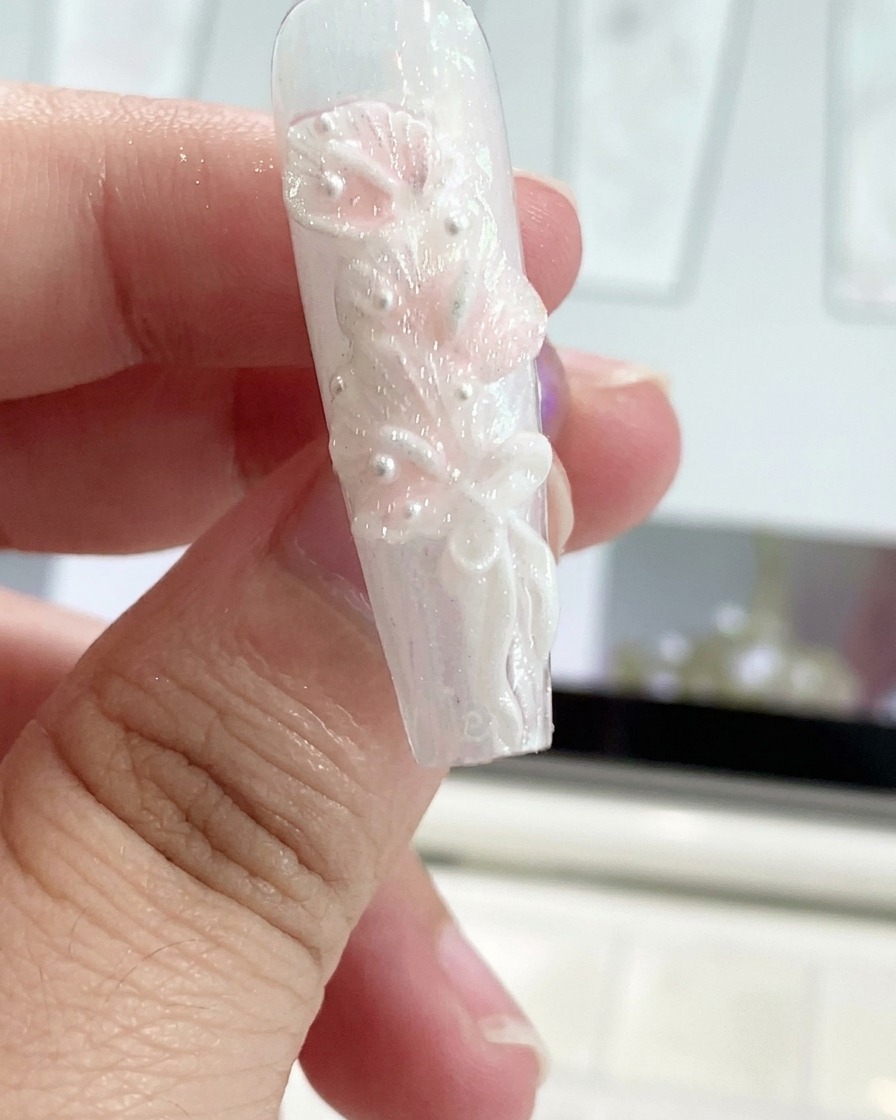 シリコンツールを使って、装飾された爪の上でジェルのリボンを形作っている様子。