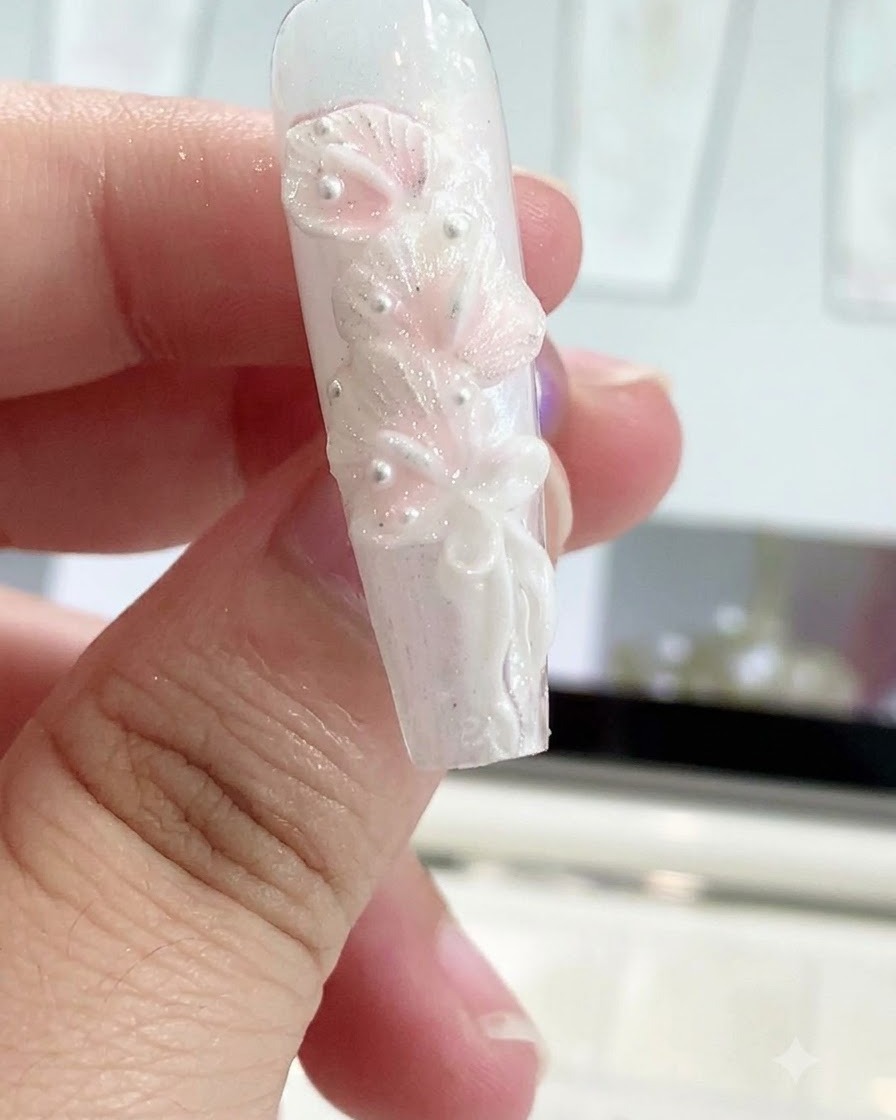 シリコンシェーピングペンを使用して、成形されたネイルデザインの上にリボンの結び目を滑らかに整えている様子。