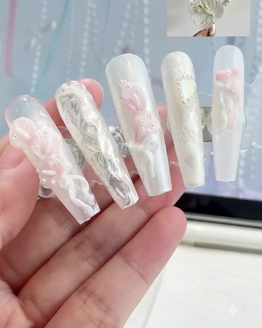 3Dの白とピンクの花のネイルアートデザインが施された複数のネイルチップが並べられているディスプレイスタンド。
