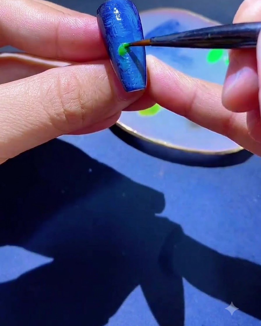 極細ライナーブラシが青いテクスチャのある爪に緑色のジェルポリッシュのスポットを塗布しているところ。