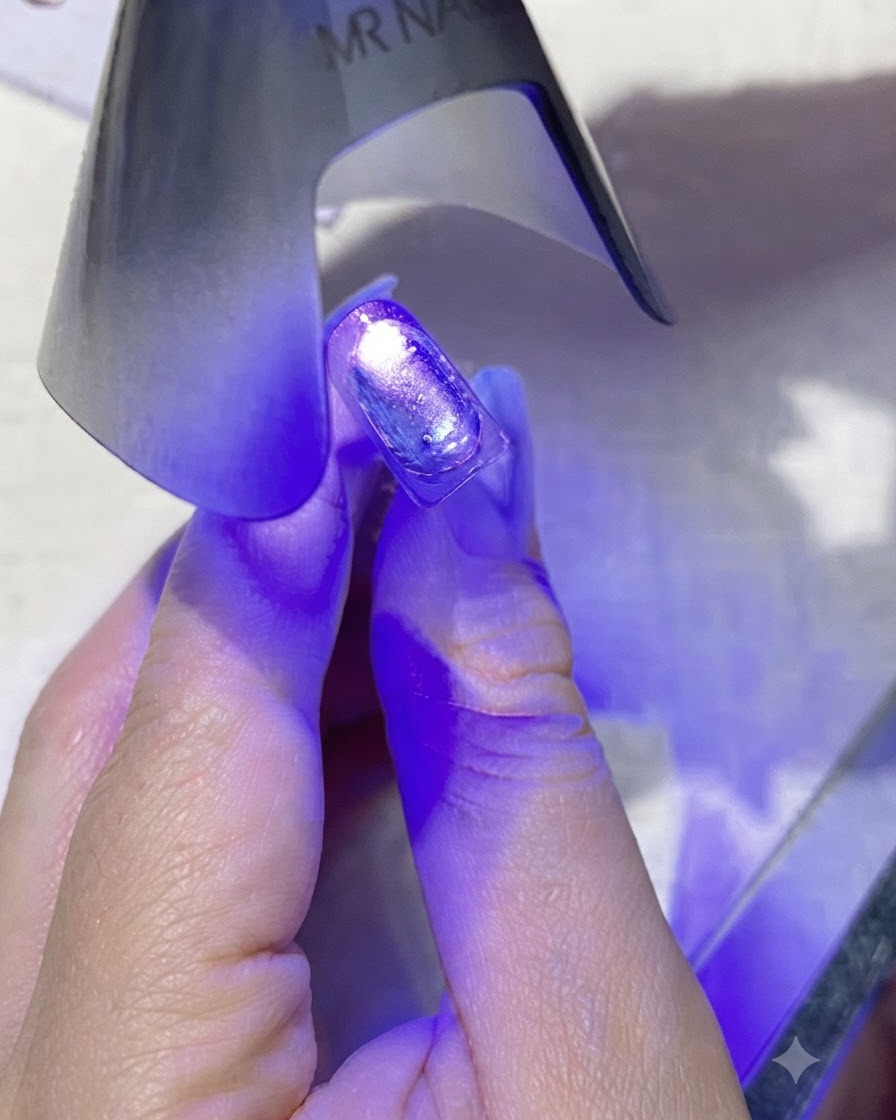 ミニパープル携帯用UV/LEDネイルランプが、コーティングされたネイルに直接紫色の光を当てている様子。