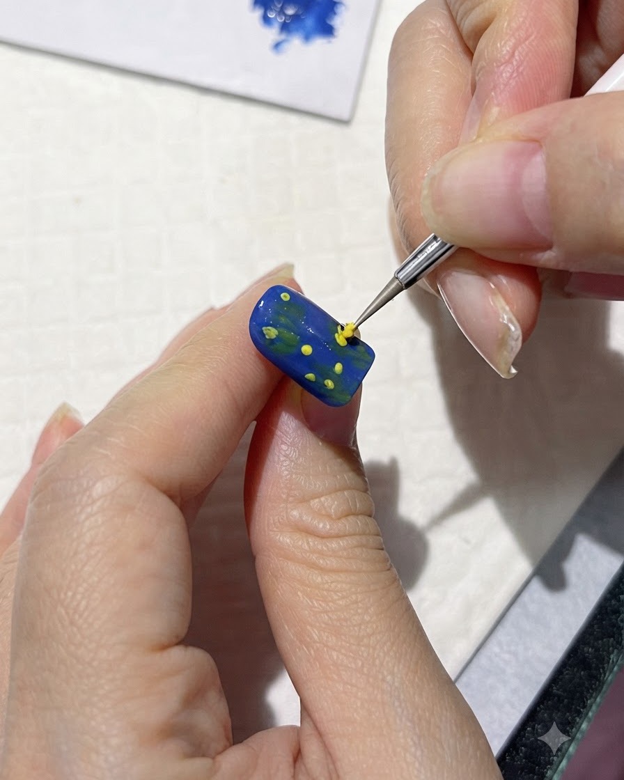 極細のブラシで、青いネイルの中心ドットの周囲にルーズな黄色い花びらの形を描いている様子。