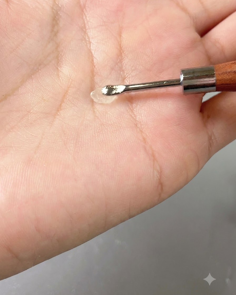 手のひらの上のハンドツールに、透明なジェルの小さな塊が乗っているところ。