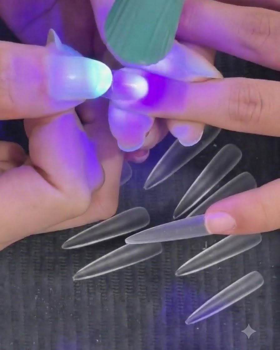 手持ちのミニ紫色のUV LEDフラッシュライトで、半硬化状態のネイルチップを照射して硬化させている様子。