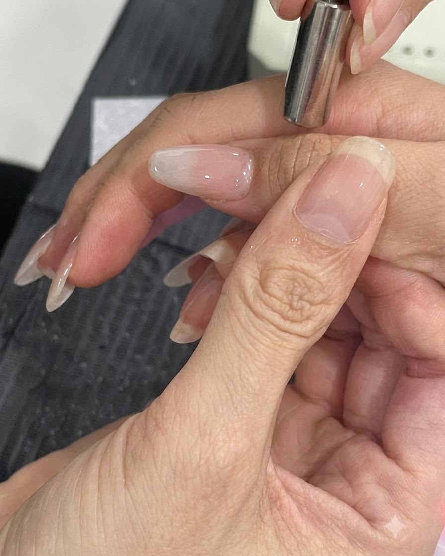 マニキュアを施した爪の側面に磁石ツールを近づけて、キャッツアイのきらめき粒子を移動させている様子。