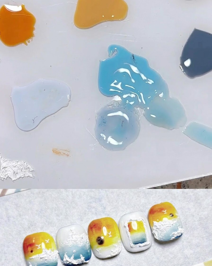 パレット上にペールイエロー、オレンジ、ブルーなどの様々なジェルカラーのドットが並び、その横にネイルアートのサンプルが置かれている様子。