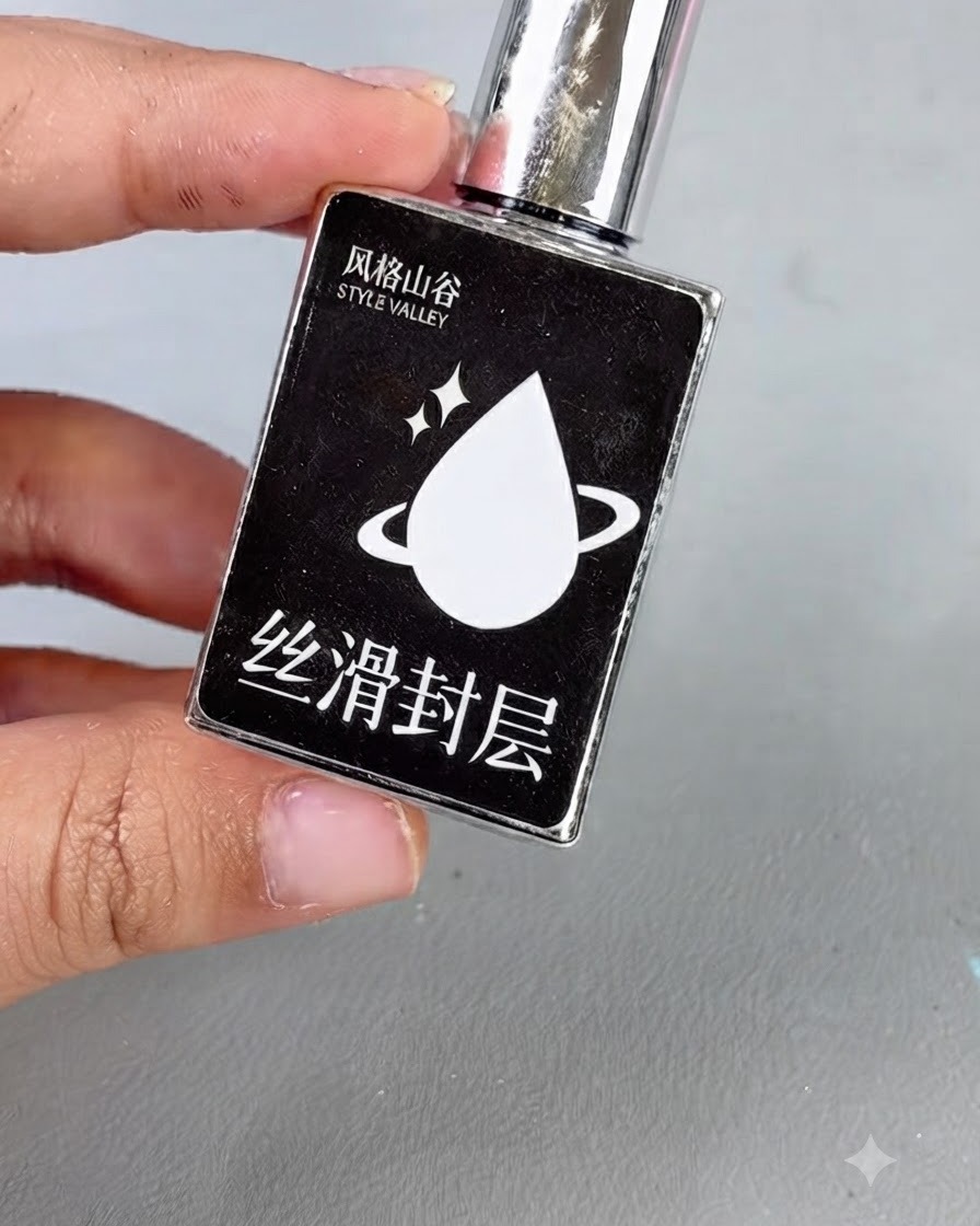 シルバーのキャップと白い水滴のアイコンが付いた黒いボトルで、スムーズトップコートジェルとしてテキストラベルが貼られている様子。