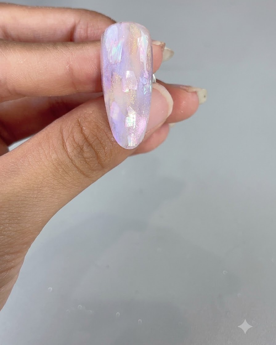 光沢のあるパープル水彩とシェルのデザインを特徴とする完成したアーモンド型のネイル。