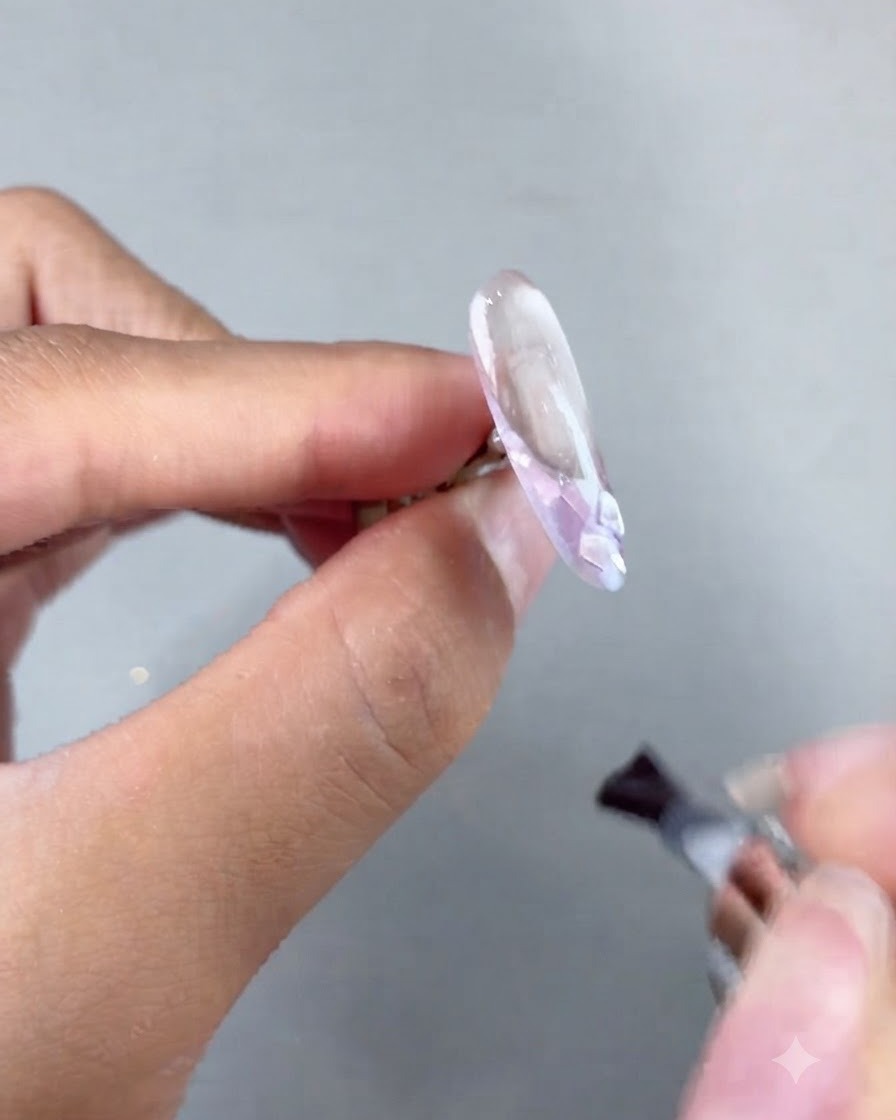 硬化の前に装飾されたネイルエクステンション上にソフトビルダージェルを塗布しているブラシ。