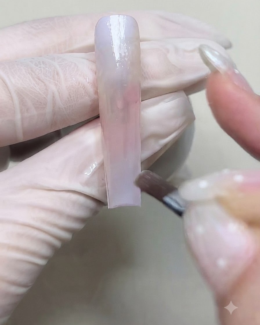 ブラシを使って、ネイル上のグラデーションの移行を深めるために2層目のカラージェルを塗布している様子。
