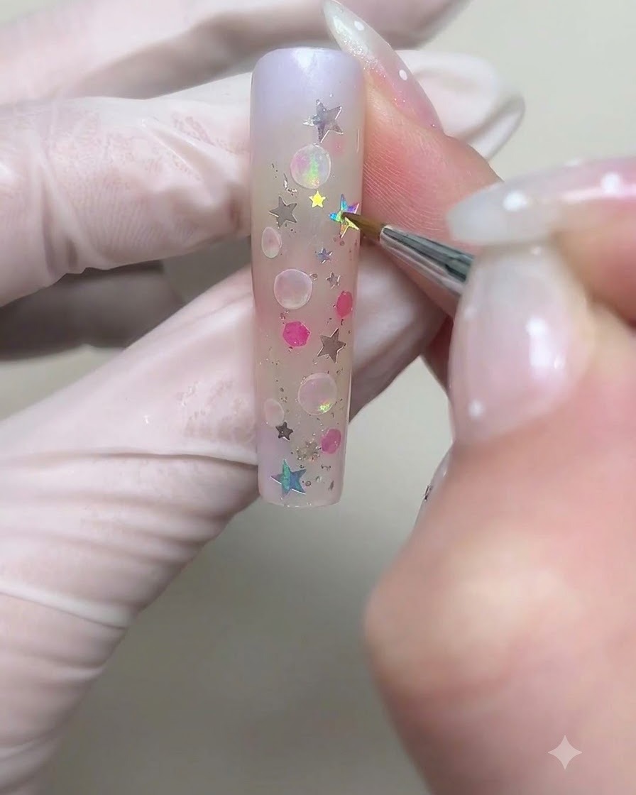白いクリームジェルを使って、ネイル上に大きめの円形のバブルのアウトラインを細いブラシで描いている様子。