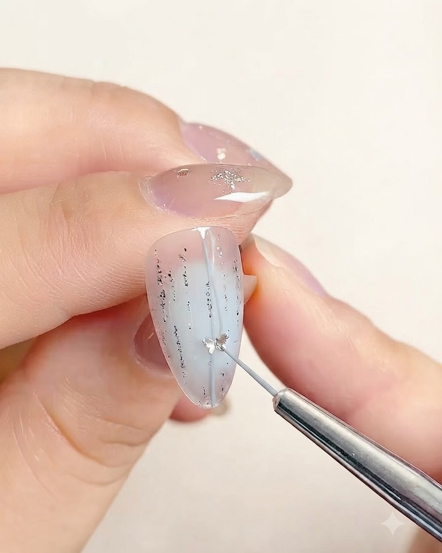 精密ツールを使って、デコレーションされた爪の中心のシルバーラメラインに沿って小さな星型のシールを置いているところ。