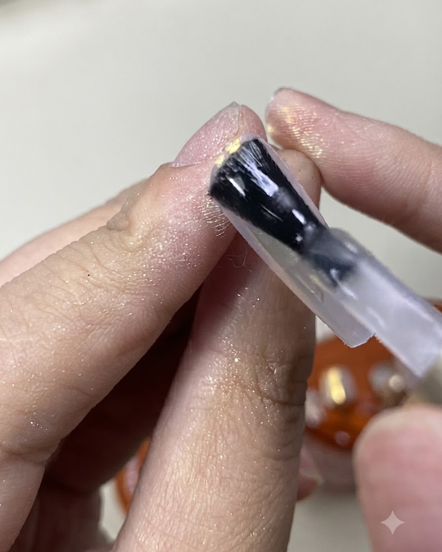 きらめくオーロラパウダーのネイルの仕上げにマットトップコートをブラシでペイントしている様子。
