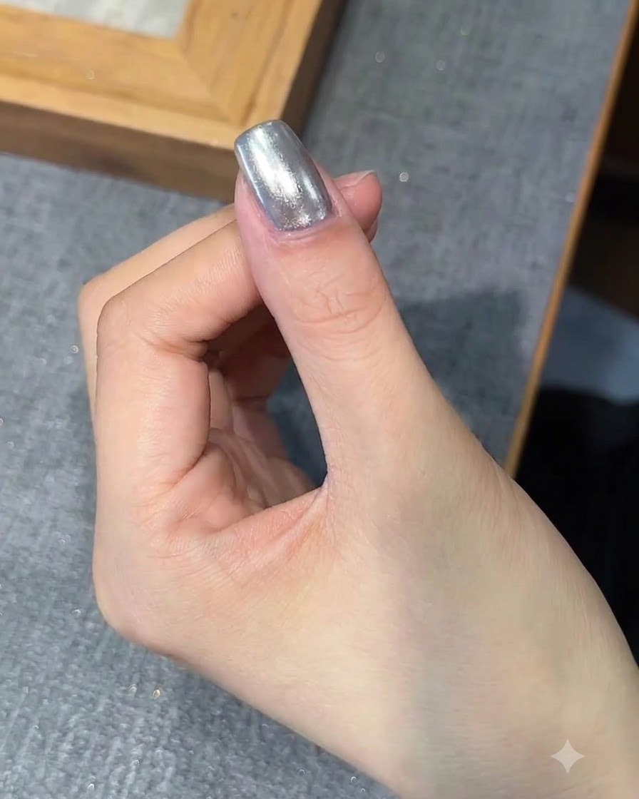 クローム仕上げの爪の上にブラシでベースジェルの層を塗布している様子。
