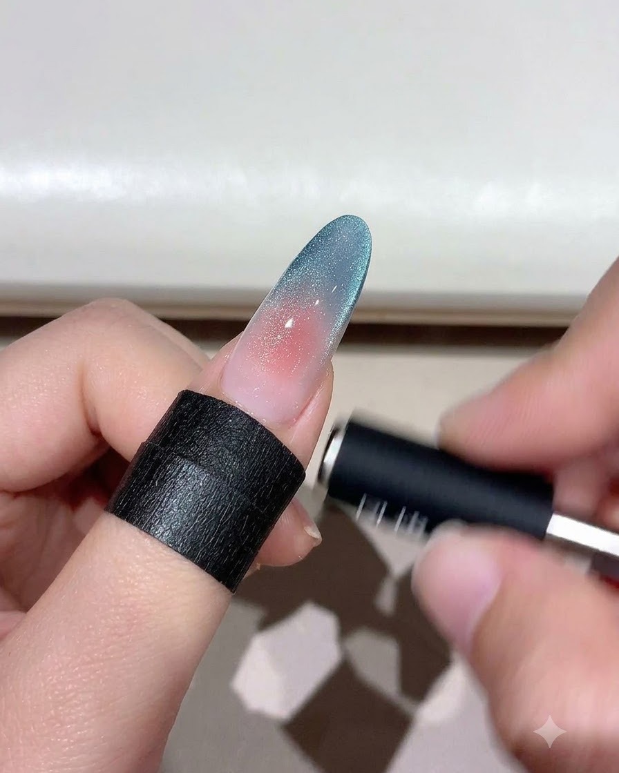 シマー粒子を形作るために、グラデーションキャッツアイネイルの上にかざされている磁石ツール。