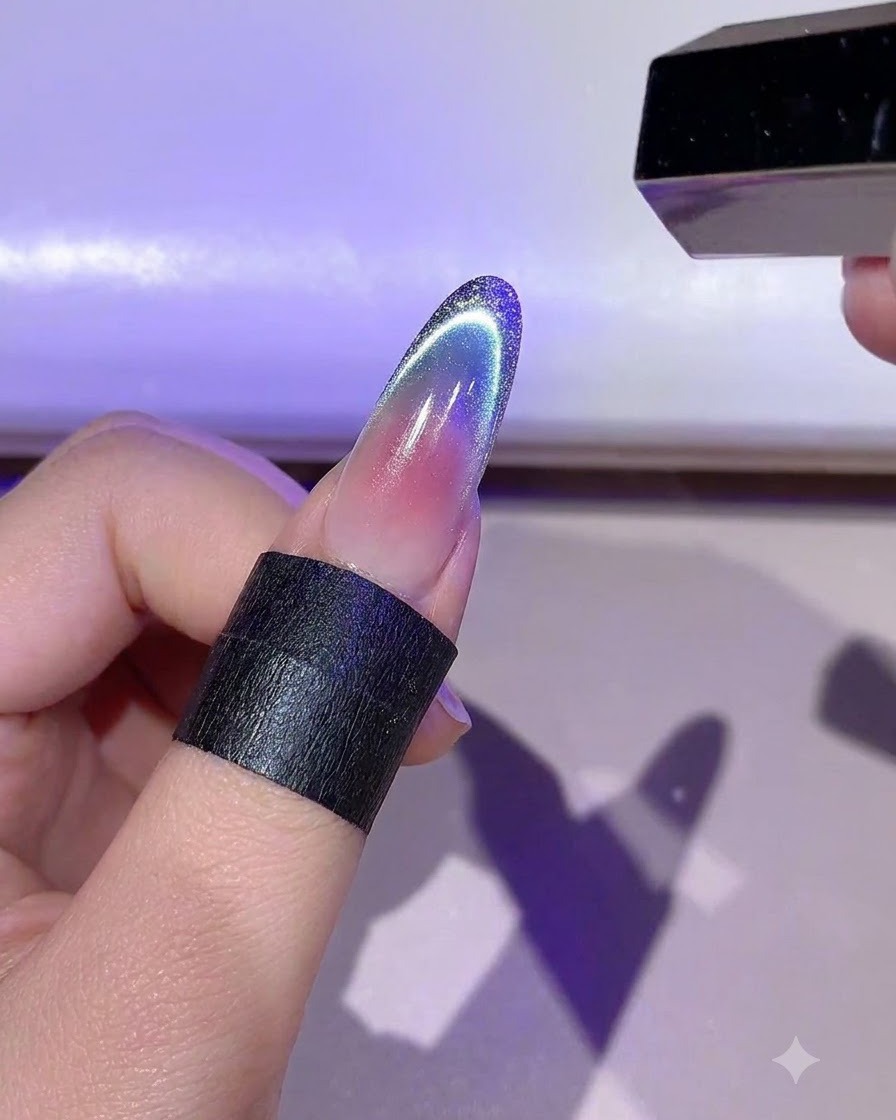 爪の上の詳細なゴールドジェルのアウトラインをミニLEDランプで硬化させている手を保持している様子。