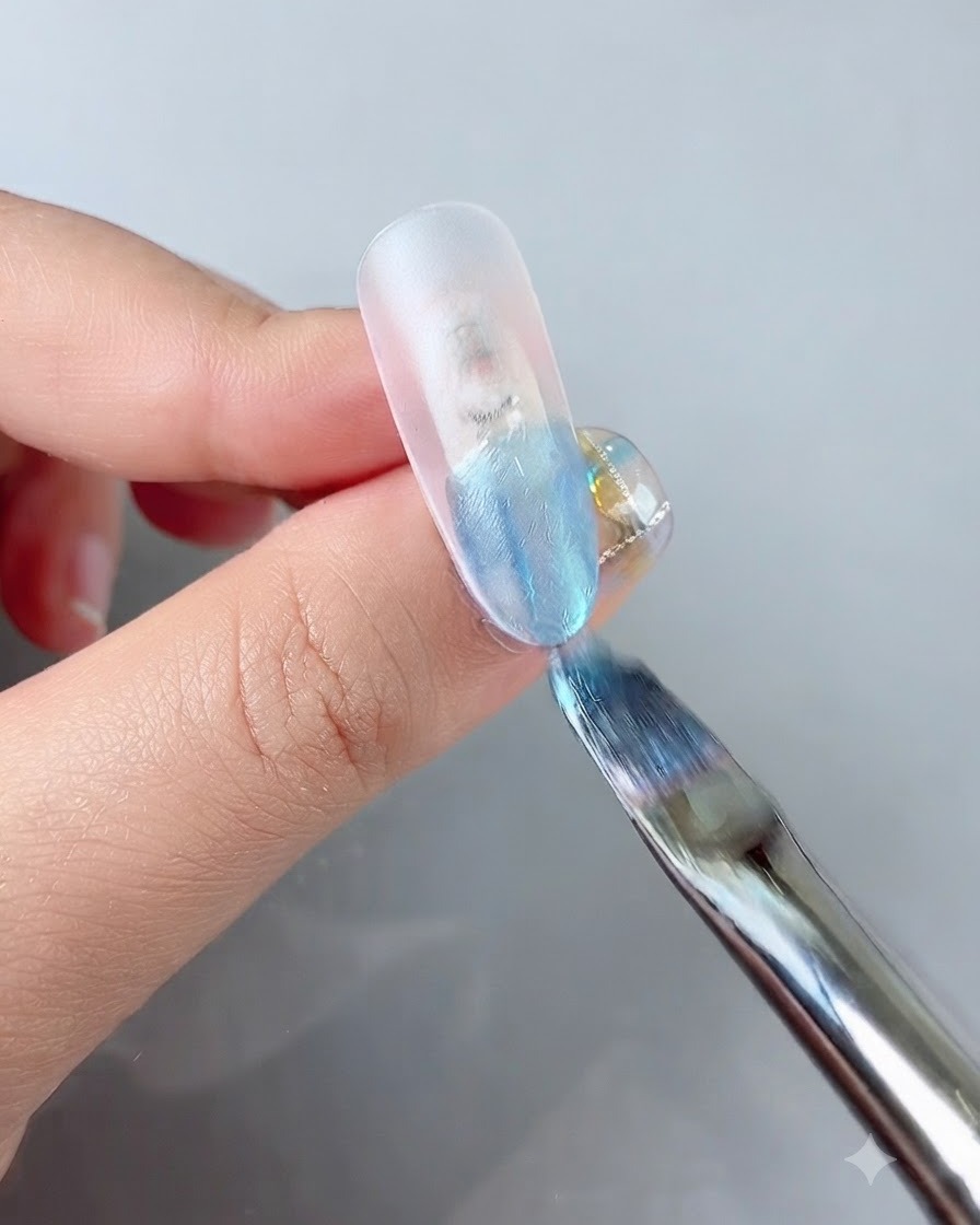 クリアネイルチップの先端に鮮やかなブルーのカラージェルを塗布しているネイリストの筆。