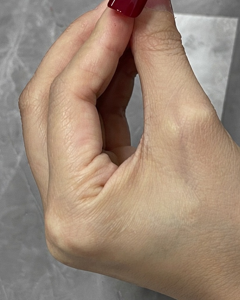 Ein Korrekturpinsel wischt verlorenes rotes Gel um die Ränder einer Nagelspitze ab.