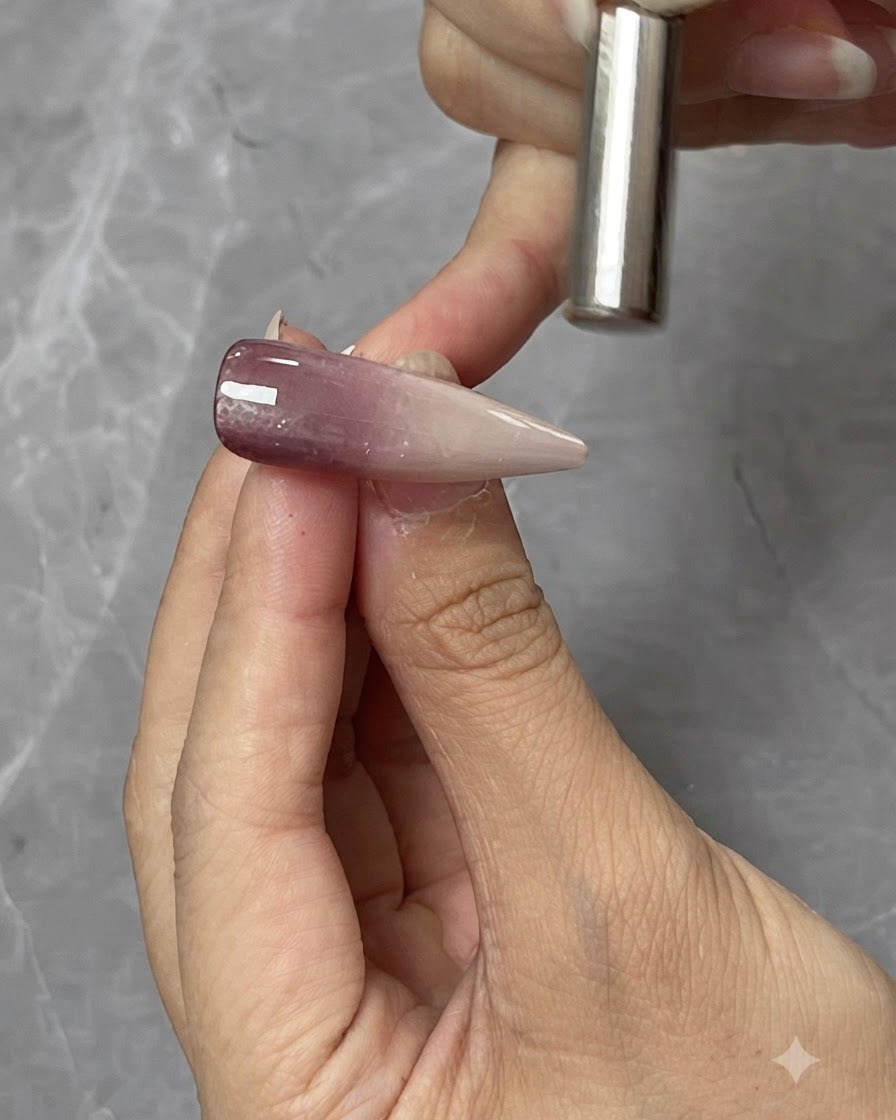 Ein Zylindermagnet wird dicht über einer Cat-Eye-Gel-Nagelspitze gehalten, um die magnetische Lichtreflexion zu formen.