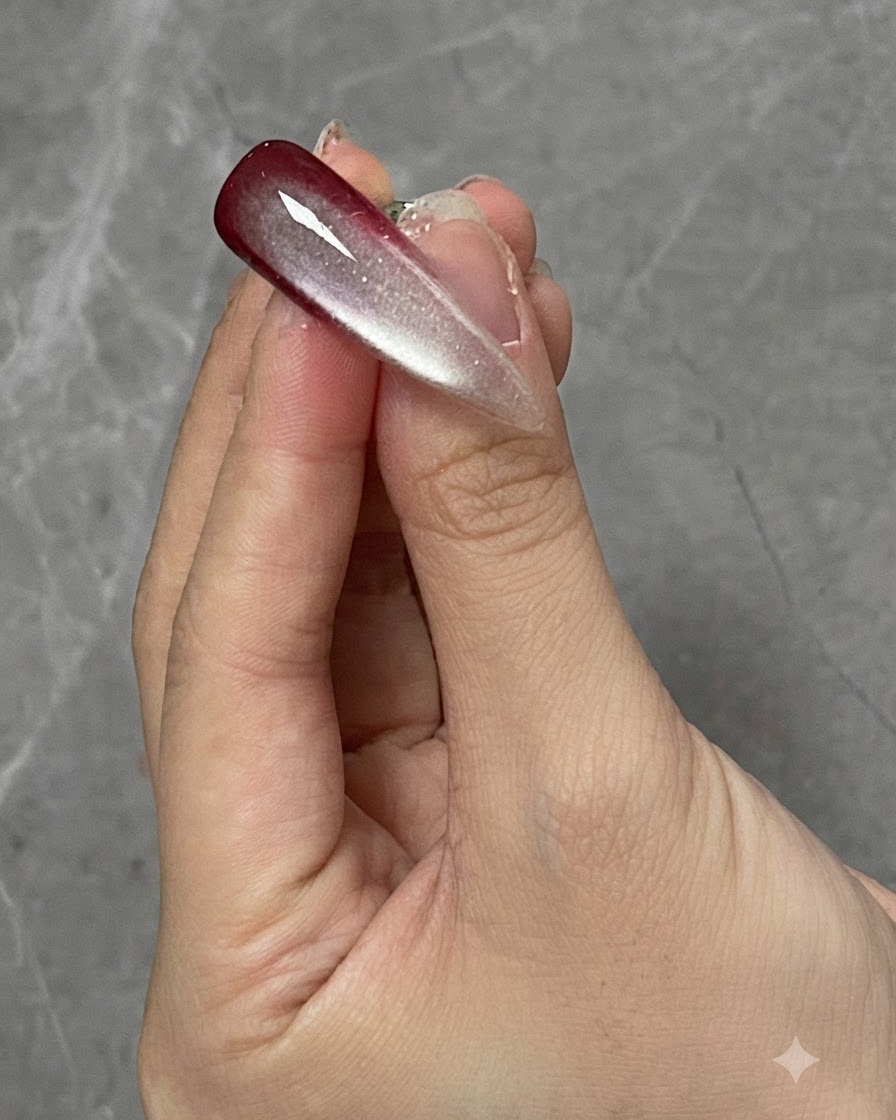 Ein Finger mit einem ausgehärteten Ombré- und Cat-Eye-Nageldesign unter einer Curing-Lampe.