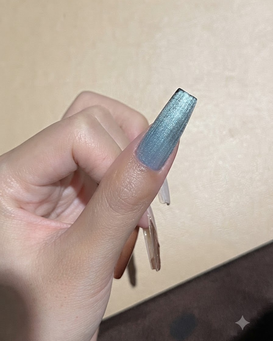 光の反射ラインを微調整するために、強力な磁石がブルーのキャッツアイジェルネイルの近くに保持されている様子。