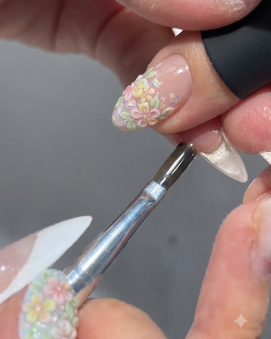 ブラシが完成したフラワーネイルデザインの上に光沢のあるトップコートを塗布している様子。