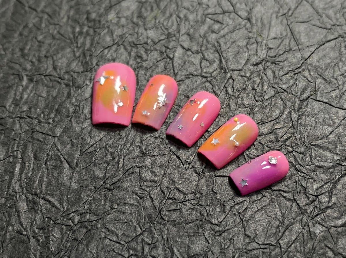 シルバーの星のアクセントがある、ピーチとパープルのグラデーションの5つのネイルのフルセットをとらえたパンショット。