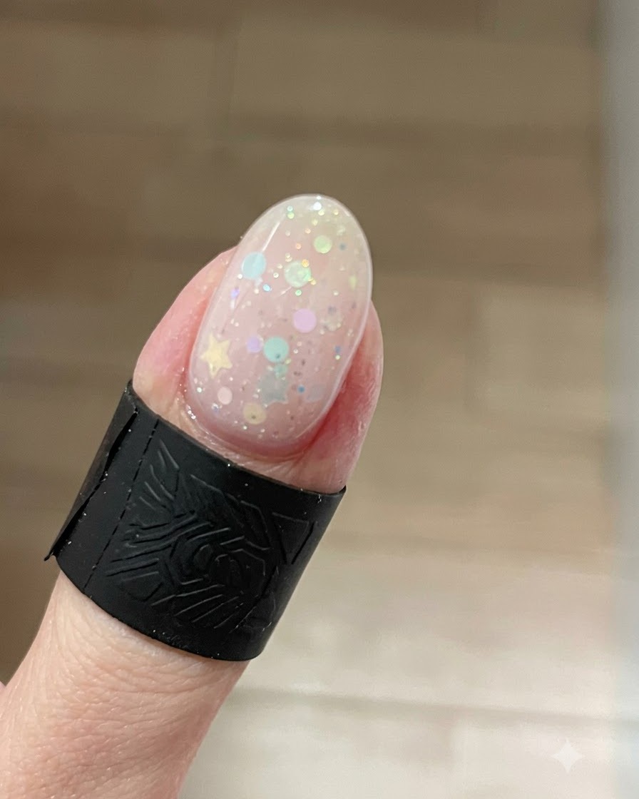 星型グリッターの上で、爪先に明るいラメが集中し、美しく輝くキャッツアイ効果が現れている爪のクローズアップ。
