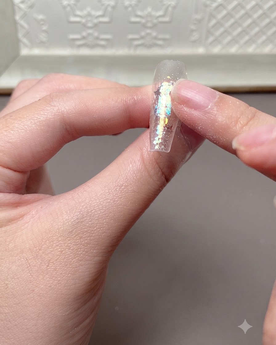 UVまたはLEDランプでの硬化後、硬化したネイルエクステンションの表面を指で軽く押して確認している様子。