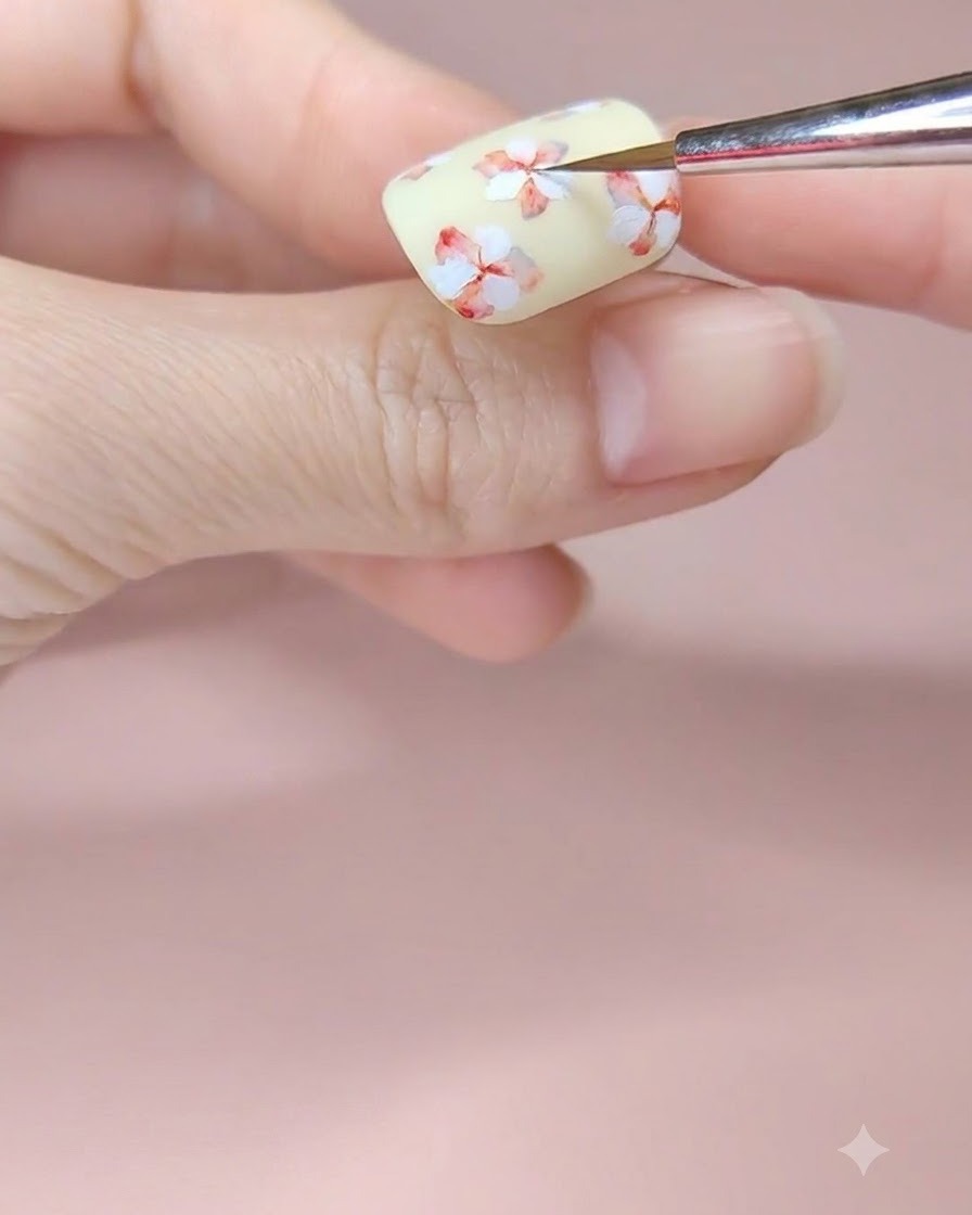 中央の重ねた白いお花の中心に赤い水彩絵の具をのせてグラデーションを作っている様子。