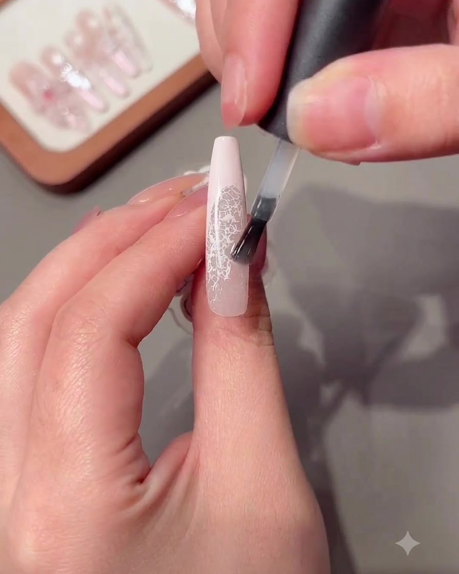 長いマニキュアの爪の上にクリアなビルダージェルをブラシで塗布している様子。