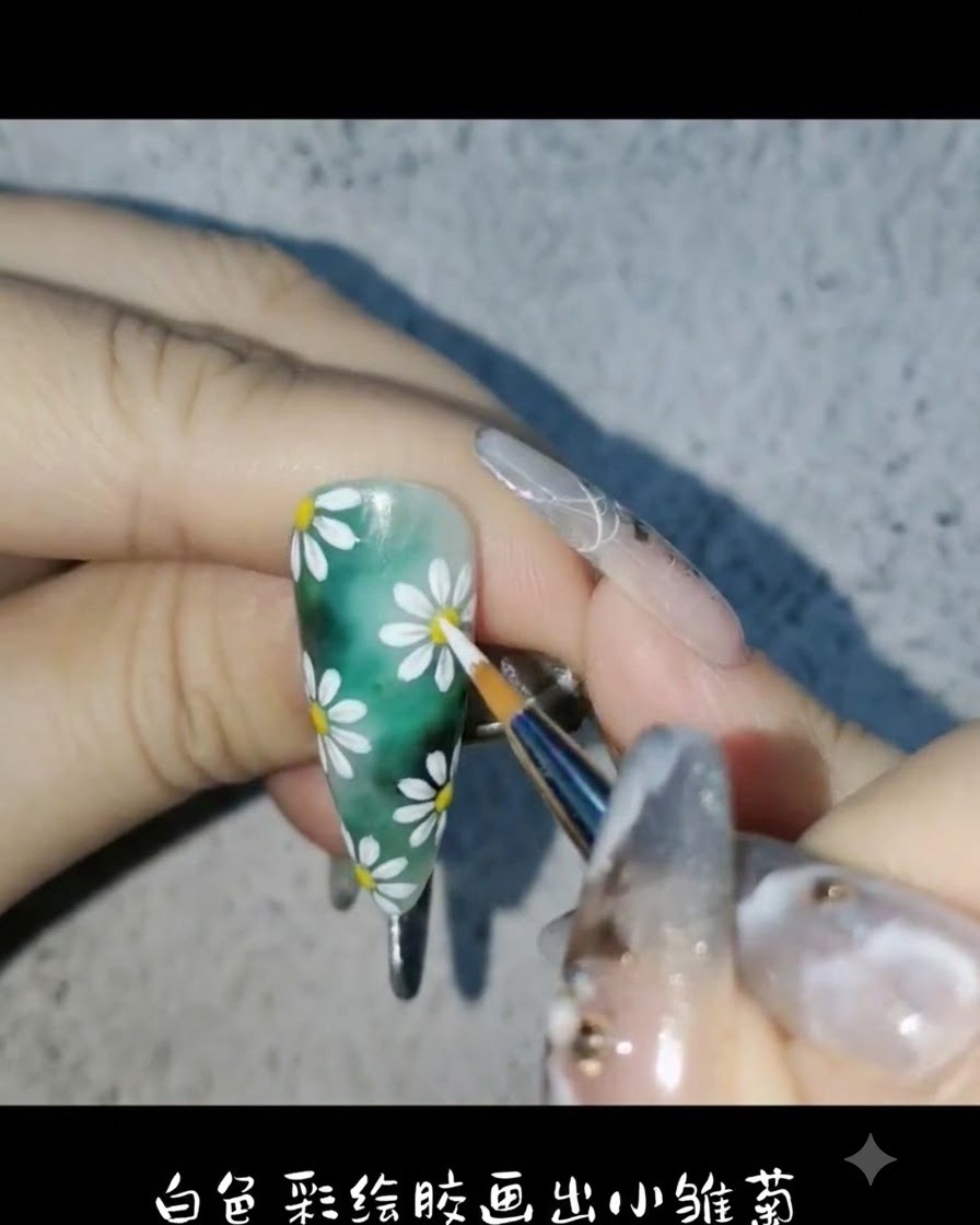 ライナーブラシとホワイトのペイントジェルを使い、グリーンのネイル背景に繊細なデイジーの花びらを描いている様子cite: 1。