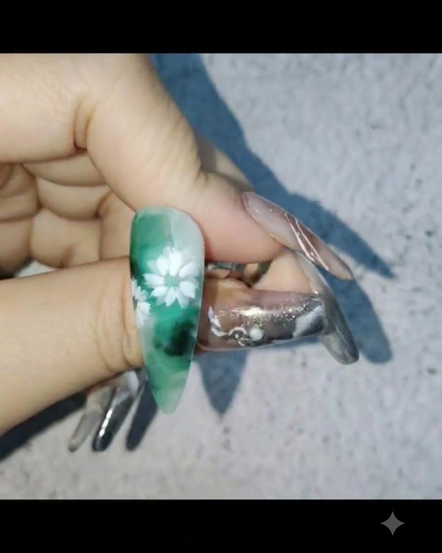 白いデイジーネイルアートが施されたネイルを片手で持ちながら、保護用のビルダージェルを塗布している様子。