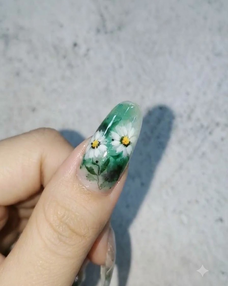 グリーン背景に白いデイジーと葉が描かれ、表面に艶やかな3D水滴が輝く仕上がりのネイルデザイン。