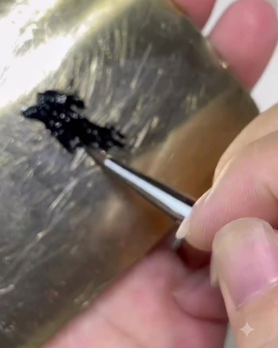 パレットからブラシボディのおよそ3分の1ほどに黒いジェル製品を含ませているネイルブラシ。