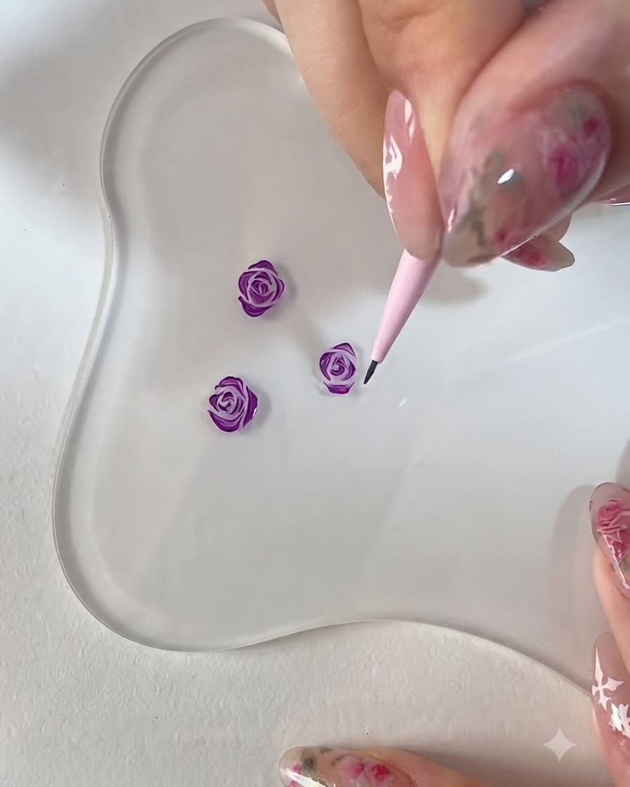 クリアなパレット上で、ピンクのディテールブラシを使用して3Dで描かれたパープルローズのエッジを整えているクローズアップ画像。