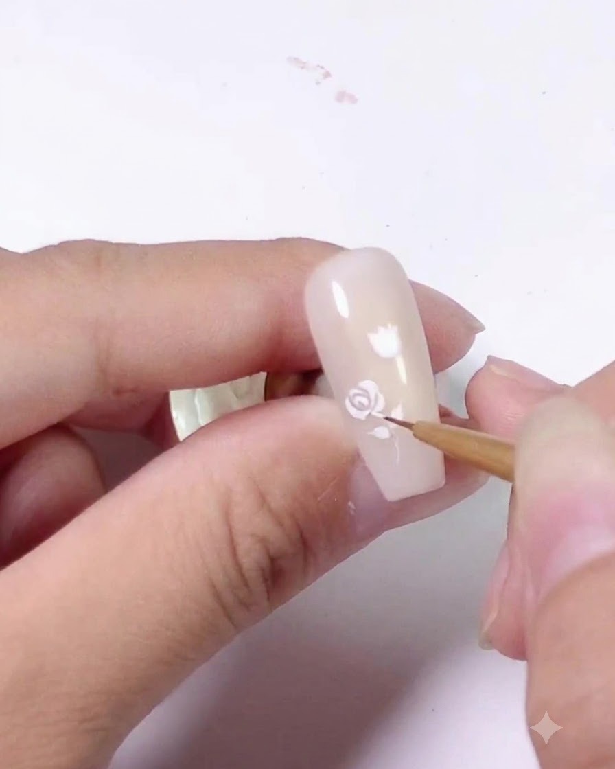 ライトピンクのネイルの上部に描かれた、完成したホワイトローズのデザイン。