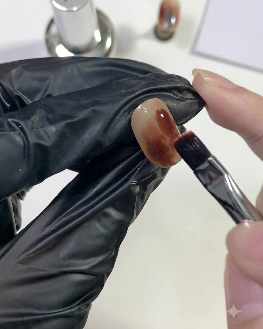 ブラシを使って、爪の一部分に深みのあるレッドのジェルを乗せている様子。