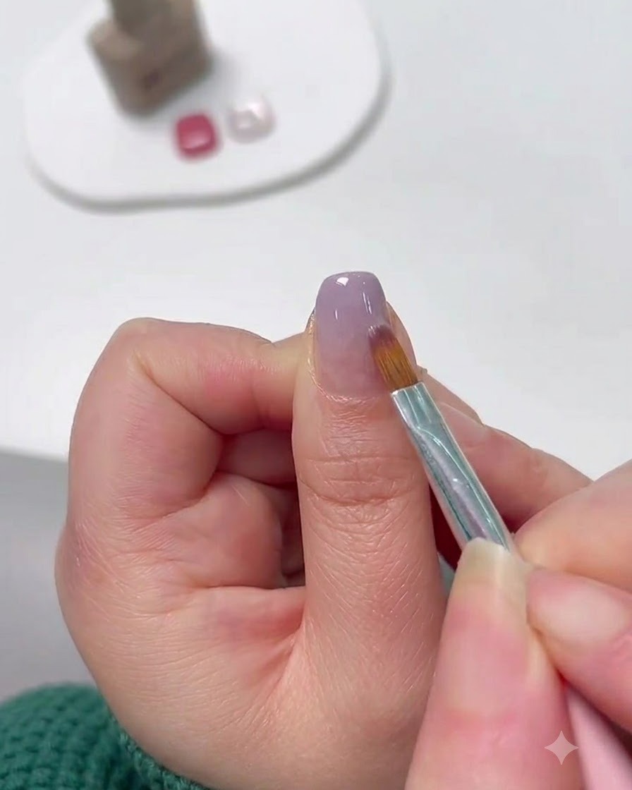 細筆を使って爪先から上に向かってラベンダーのジェルをぼかし、グラデーションを作っている様子。