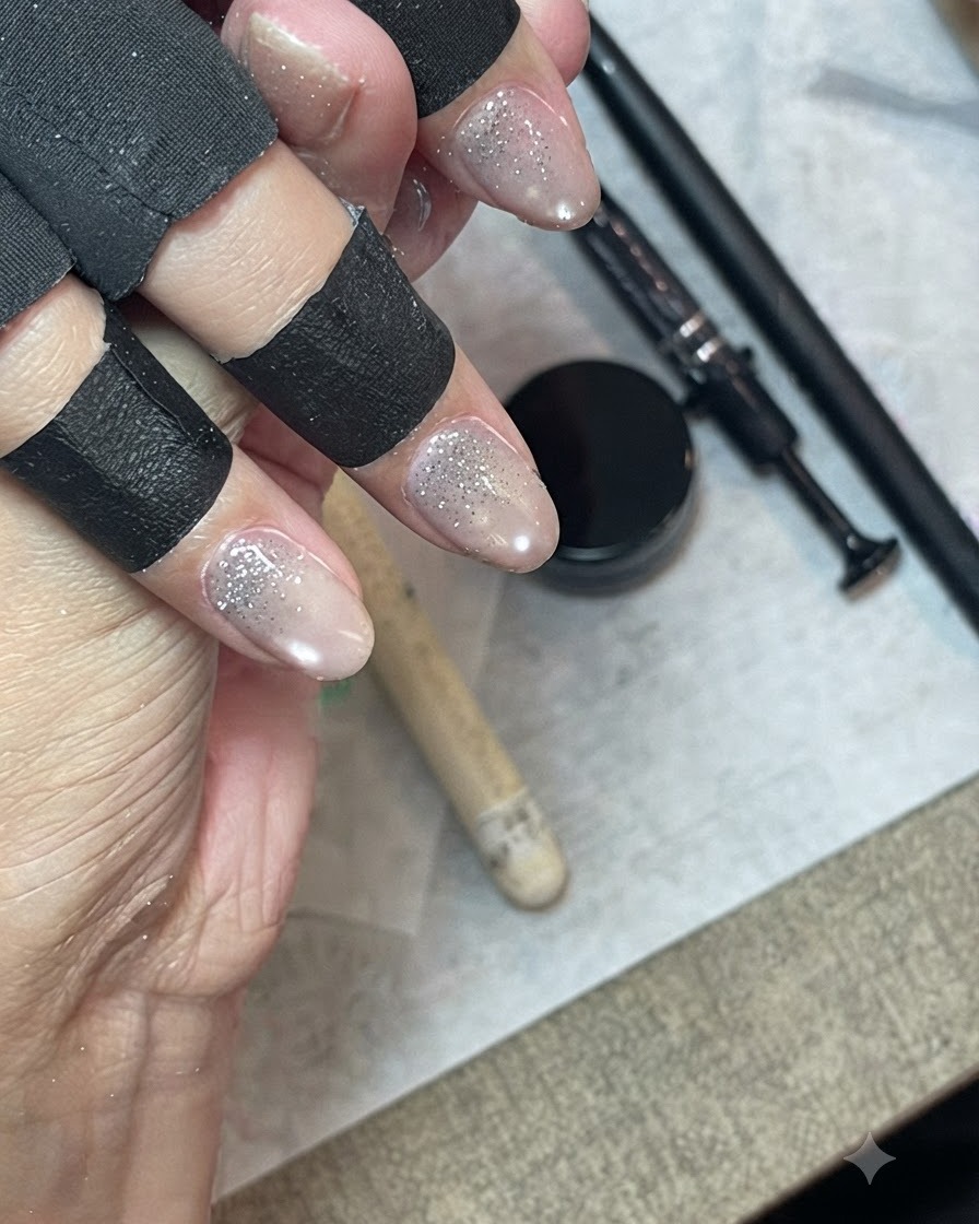 黒いフィンガープロテクターを装着した手が、細いライナーブラシを使用してグリッタージェルを羽のように伸ばしてブレンドしている様子。