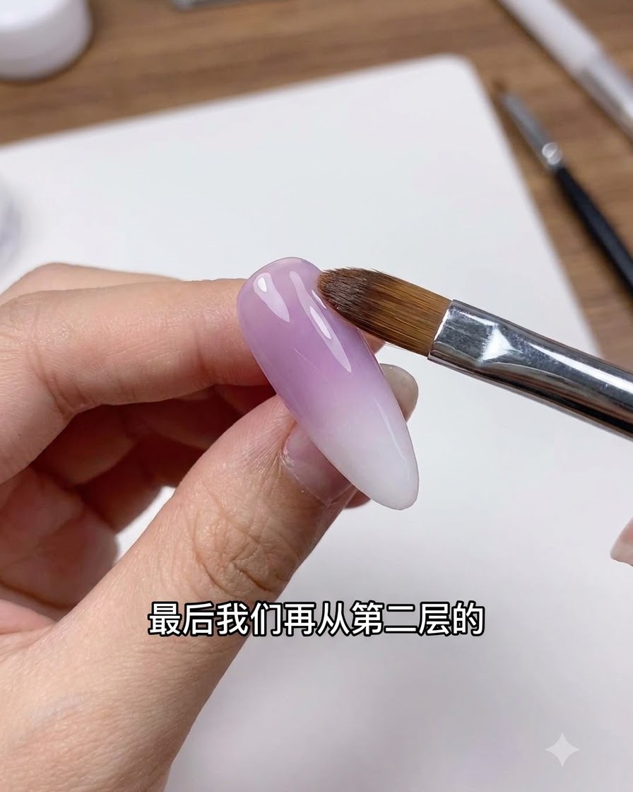 綺麗なネイルブラシが、パープルとホワイトのグラデーションネイルの移行ラインを優しくフェザリングしている様子。