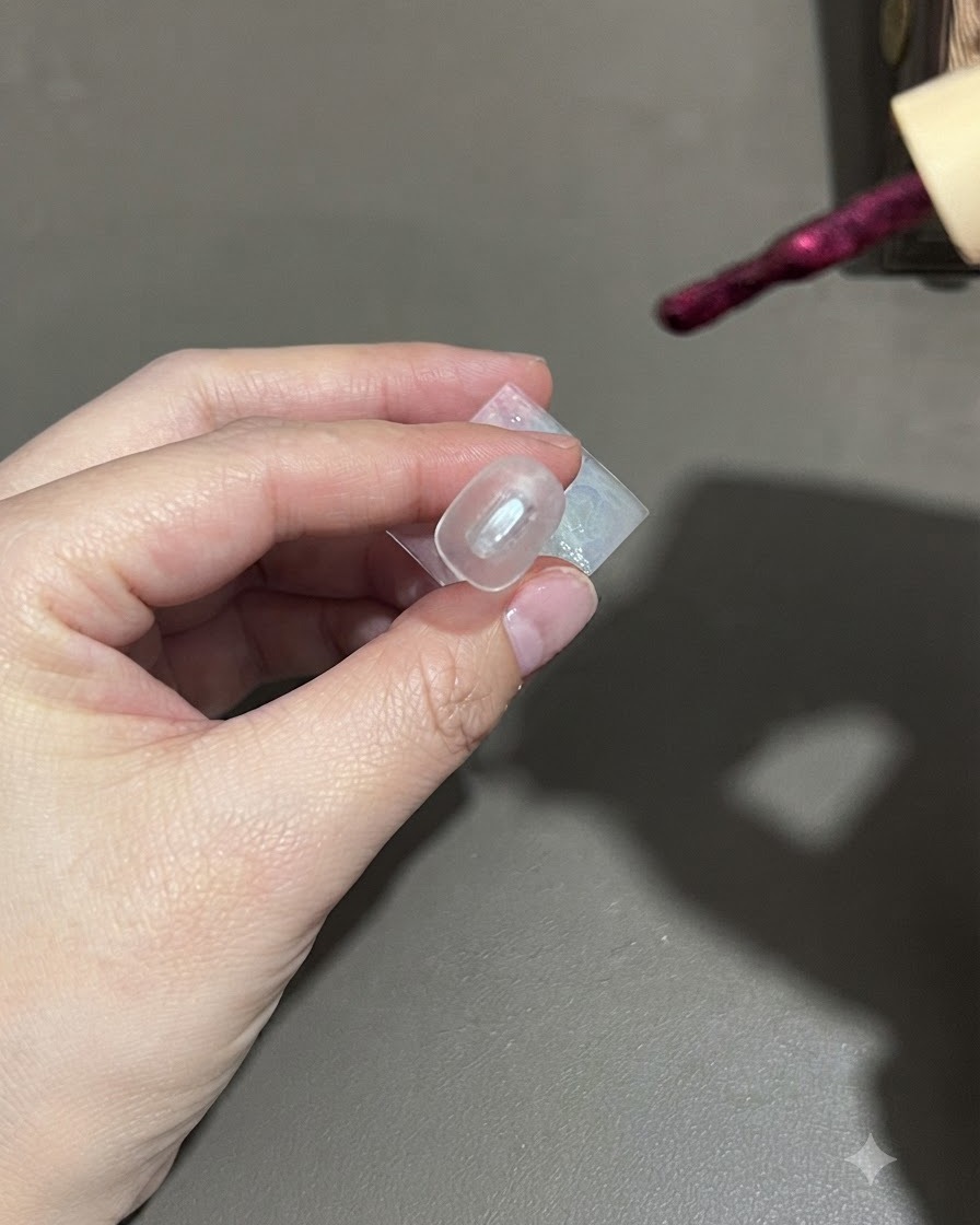 ダークパープルのキャッツアイジェルポリッシュを爪に塗布しているブラシ。