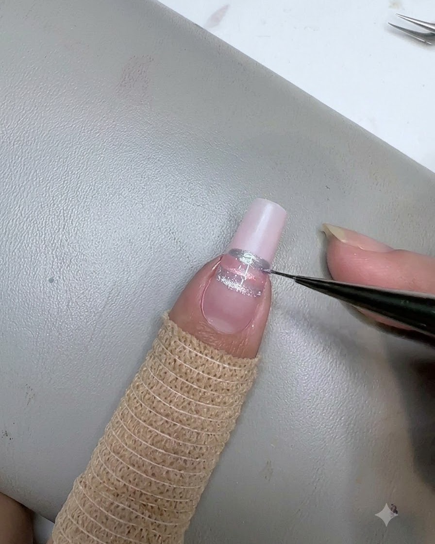 ライナーブラシを使って、ネイル上のピンクのストライプの下に3本目のブルーの水平ストライプを描いている様子。